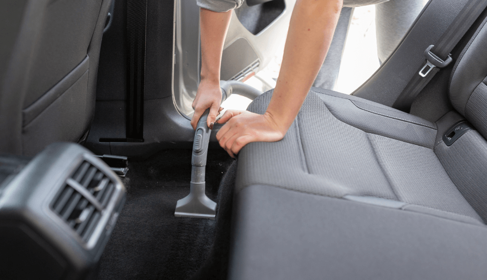 Woman vacuuming the car floor