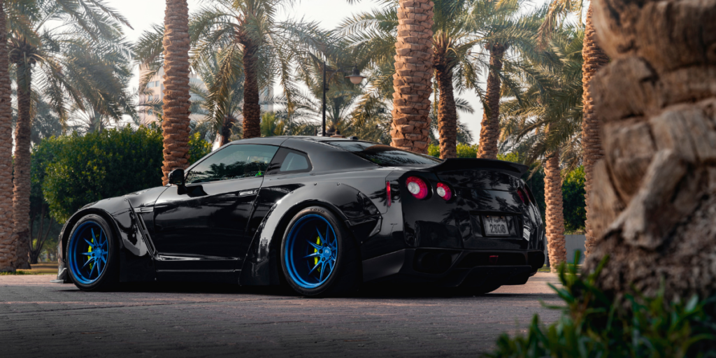 A magnificent black super car parked gracefully in a serene park, surrounded by lush green trees.