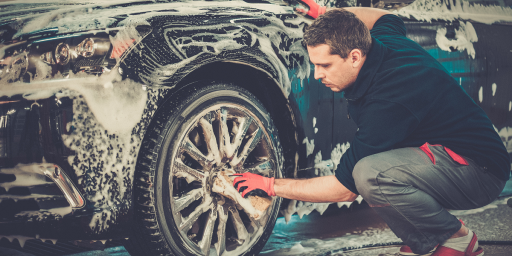 A dedicated car enthusiast takes meticulous care of his black car using soap