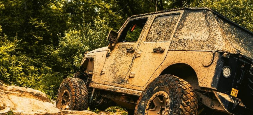 Intensely drenched in mud, a Jeep Wrangler exhibits the thrill of off-road exploration and tough riding.