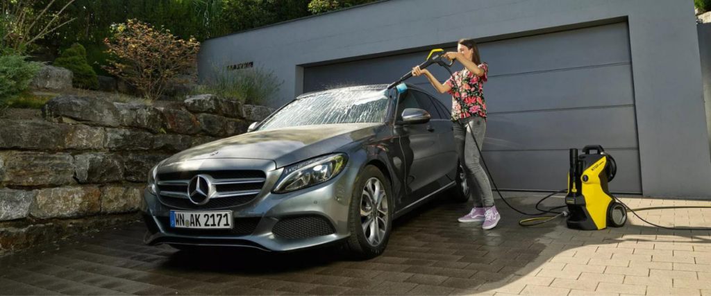 A woman diligently cleans her gorgeous Mercedes Benz using a high-pressure washer, ensuring every corner gets the royal treatment.