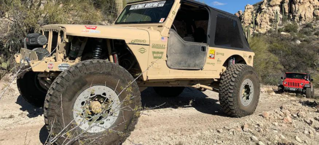 In this scenic outdoor shot, a stylish Jeep Wrangler is captured in action, traversing a rugged stony landscape during a sunny day.