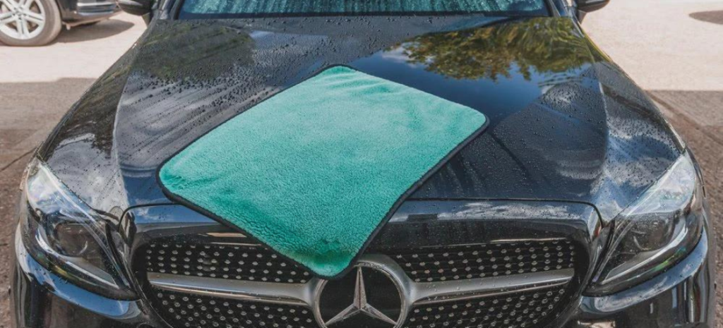 A plush Microfiber towel, strategically placed on the Mercedes car's front, is employed with utmost precision to gently dry every contour and surface, leaving no trace of water spots.