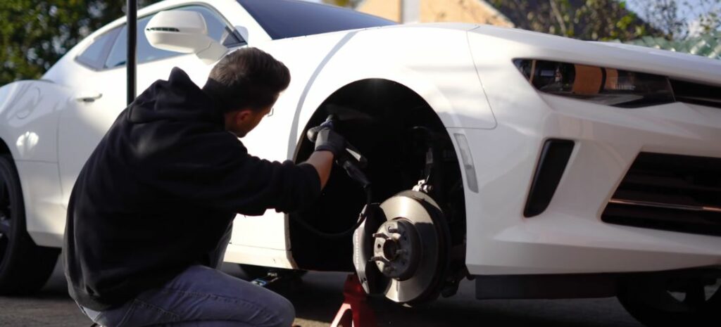 An ardent detailer is hard at work, ensuring that even the most concealed parts of their white car gleam with perfection.