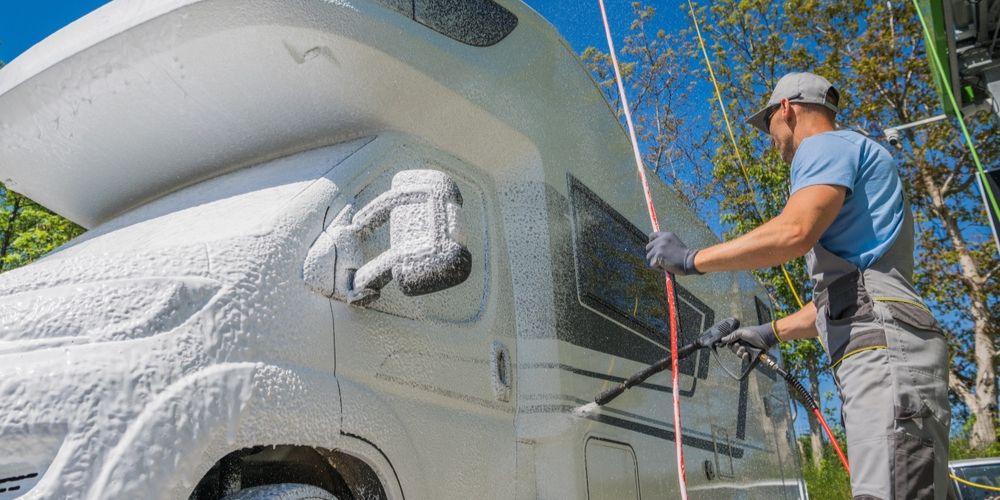 Man pressure-washing an RV completely smeared with soap as this method effectively removes stubborn stains.