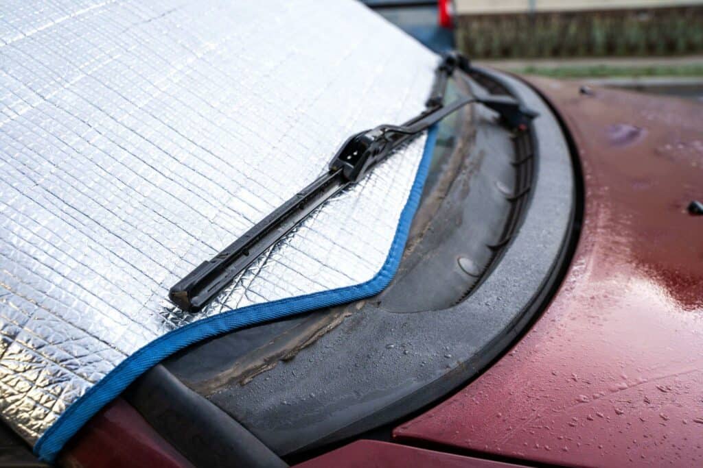 Red car's windshield covered up with a protective mat.