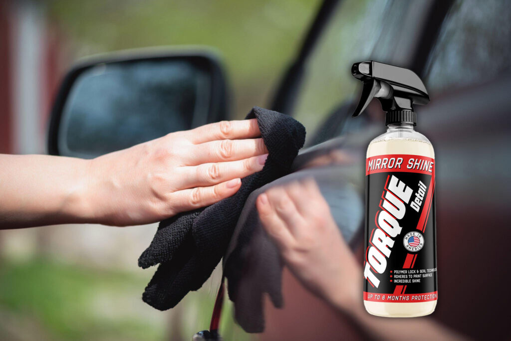 Cropped view of a hand gently rubbing the surface of the car using a soft microfiber towel with Torque Detail's Mirror Shine.