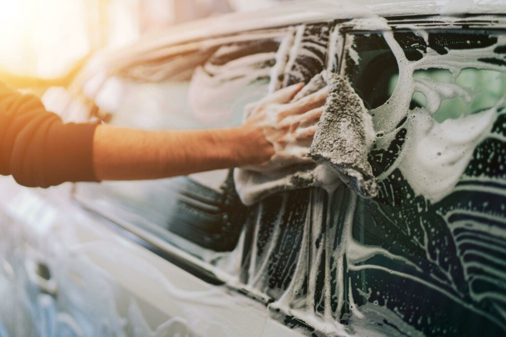 Cropped view of a man washing his car with a microfiber towel.