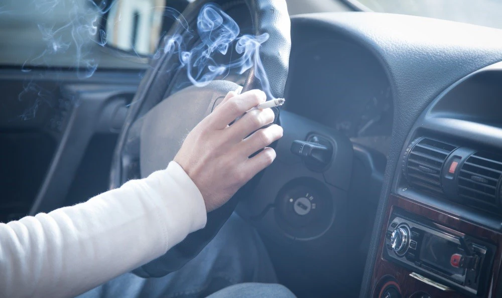 Man smoking inside the car with cigarette in his hand.