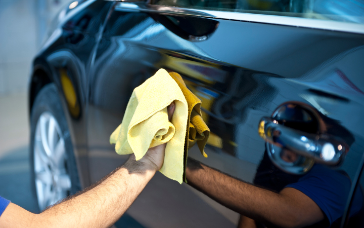 Image of a man waxing a black car