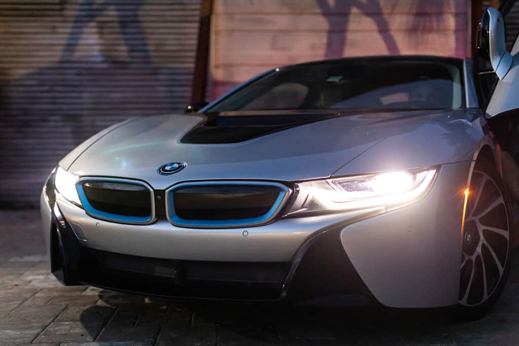 A shiny silver BMW car with its headlights on.