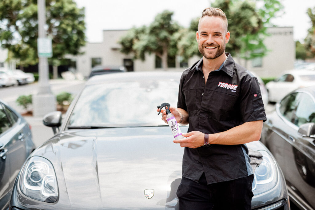 Torque Detail Ceramic Coat being carried by a man with a gray sports car behind him.