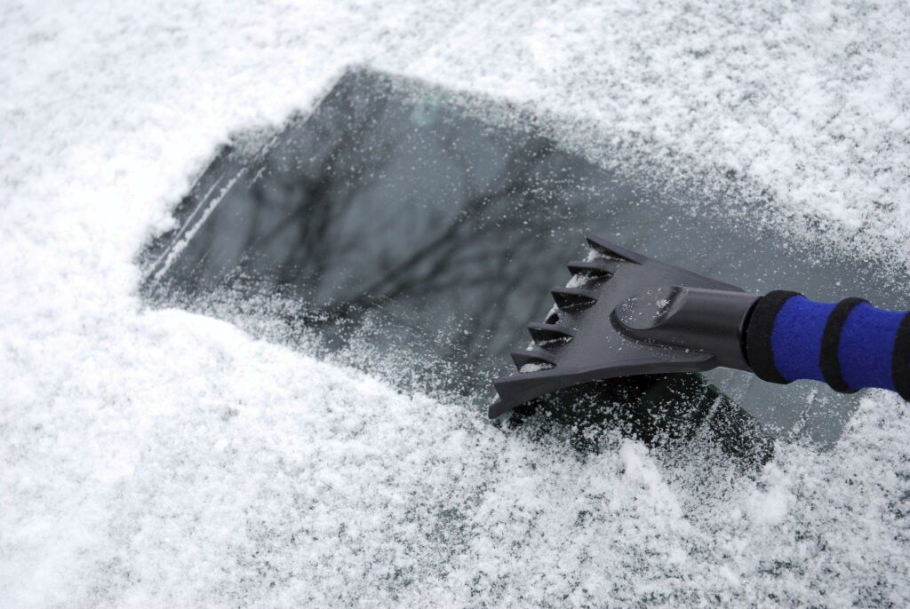 Close up view of a car's windshield that is scraped with a snow scraper.